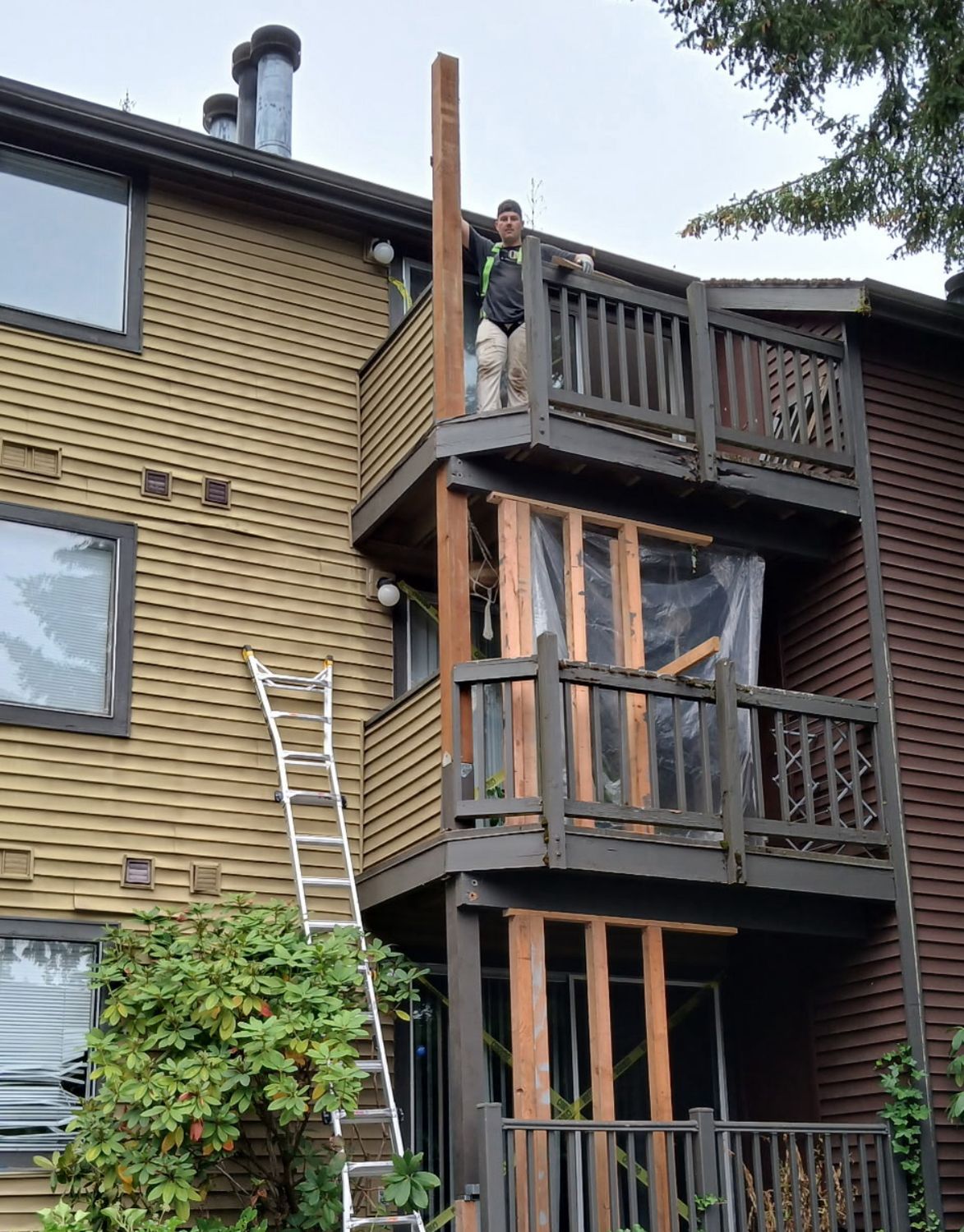 Structural post and balcony repair in progress on a three-story apartment building